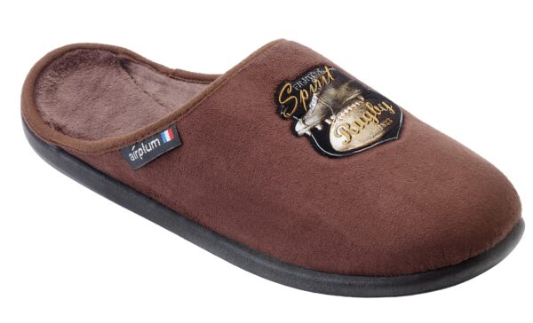 chausson de type mule en couleur marron. Il est conçu avec une doublure douce et confortable à l'intérieur. Sur le dessus, il y a un écusson décoratif noir et doré comportant l'inscription "Spirit Rugby" et un motif lié au rugby, comme une balle ou un casque. Sur le côté, une étiquette affiche le logo de la marque "airplum" accompagné d'un petit drapeau français, indiquant probablement que ce produit est fabriqué en France ou associe la marque à une identité française. La semelle semble être noire, robuste et adaptée pour un usage intérieur.