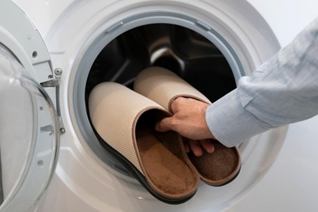 main mettant une paire de chausson en machine